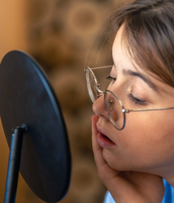 A beautiful girl looks at herself in the mirror. Skin care concept. High quality photo. Caring for your skin. The girl looks at herself in the mirror at home, in her room.