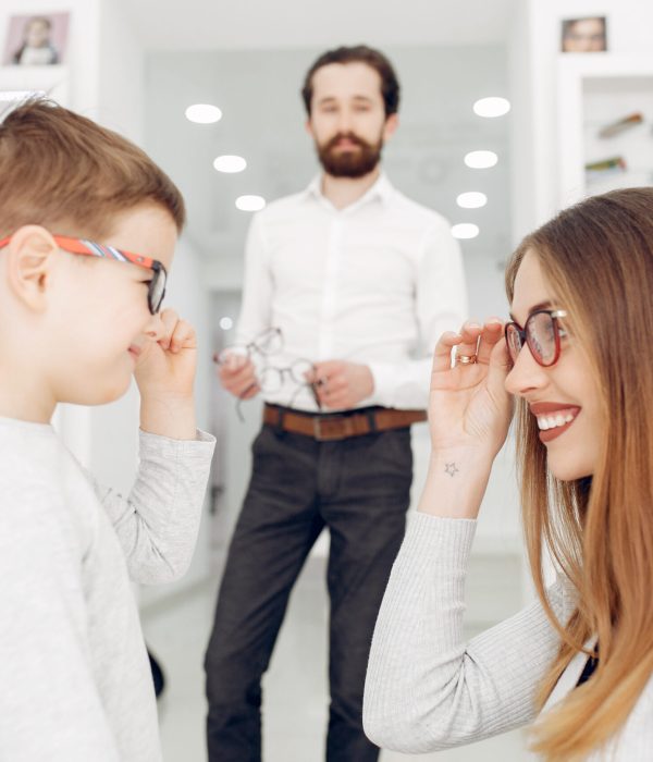 Mother with cute son. Family buy glasses. Assistant helping the clients
