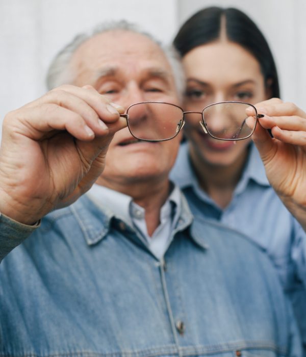 Grandfather on a gray background. Old man with granddaughter. Senior in a blue shirt.